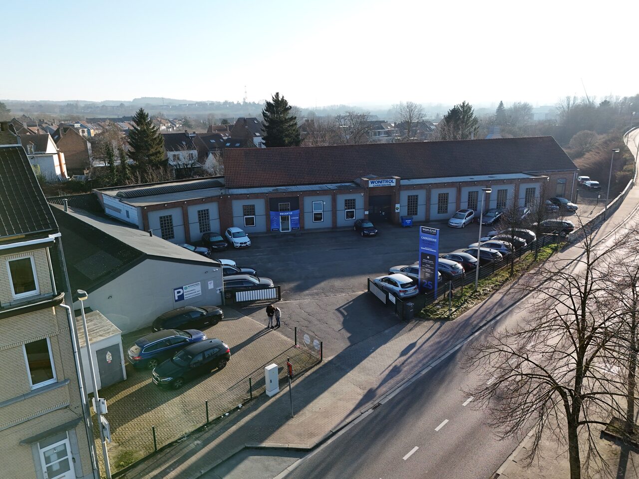 Luchtfoto van de carrosserie van Wonitrol op Stationsstraat 25: werkplaats, parking, totem aan de straat.